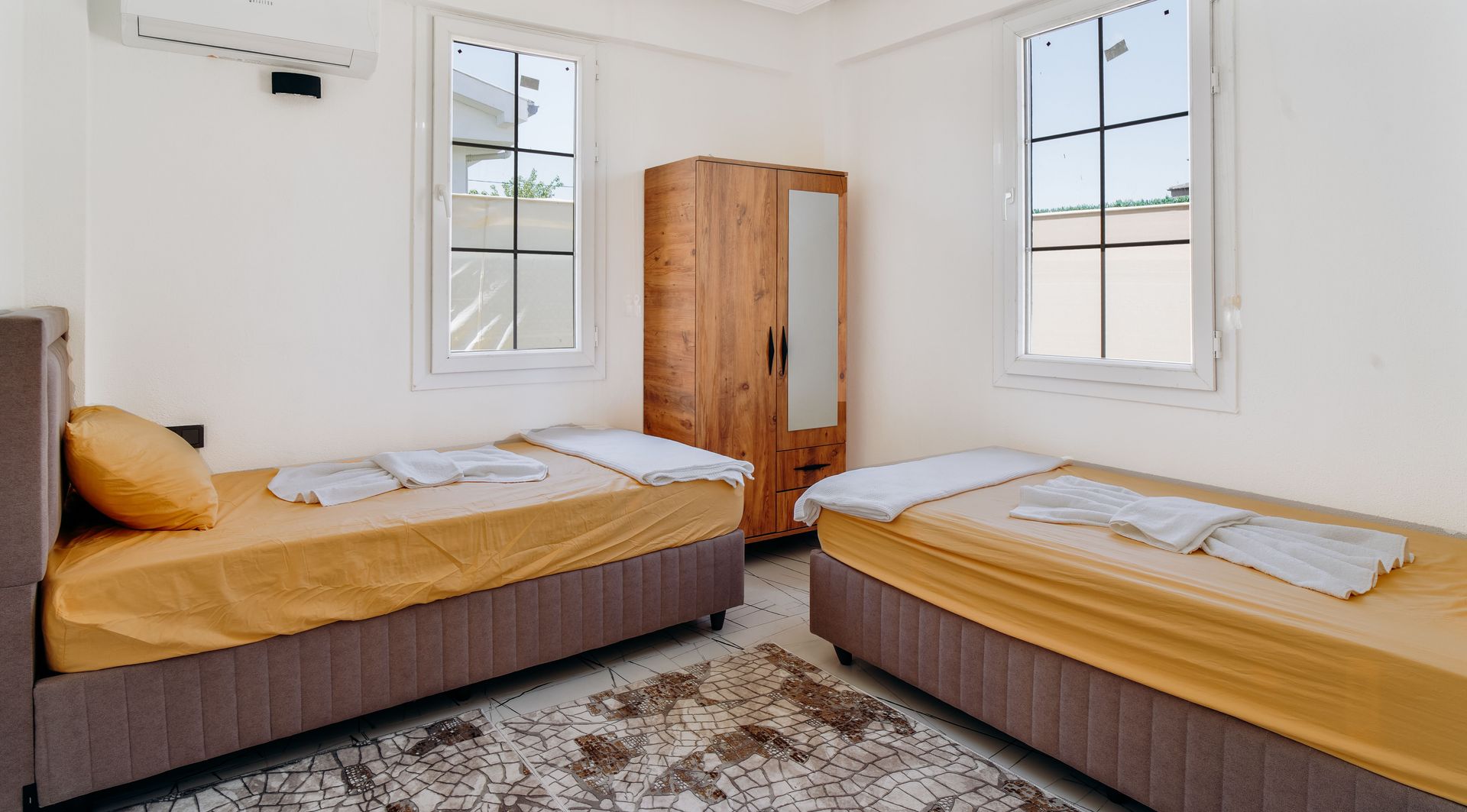 A minimalist bedroom featuring two neatly made twin beds with yellow sheets.
